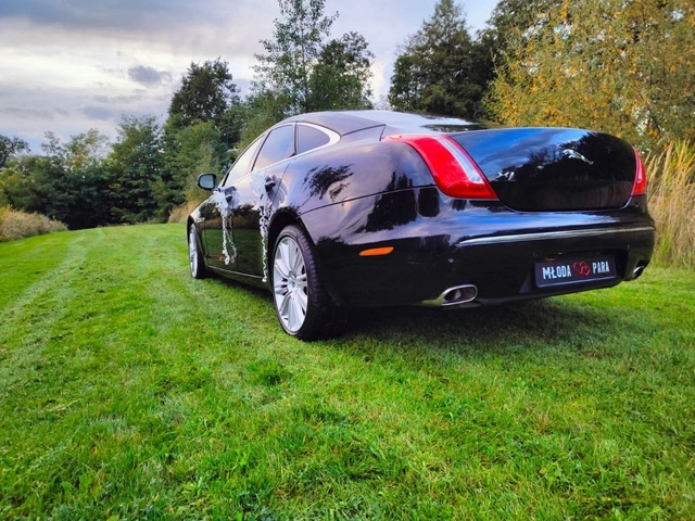 Jaguar do ślubu z białymi kokardami na klamkach